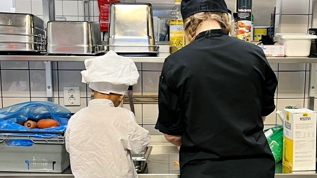 Förskolebarn i kockkläder tillsammans med kock