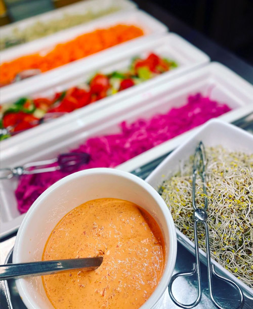 Salladsbuffé i skolrestaurang med såser i förgrunden