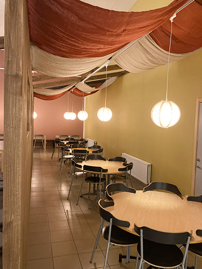Måltidsmiljö i skolrestaurangen, med avgränsade vägg och tyg som böljar mjukt från taket.