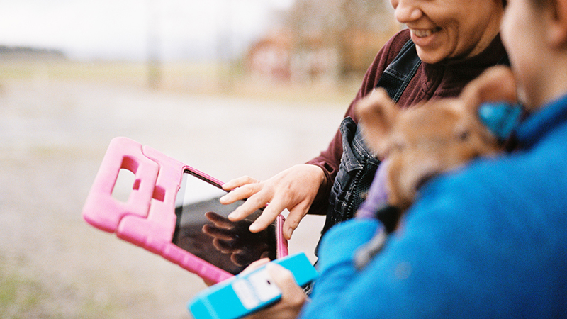 Närbild på två personer i fält, de har digitala plattor i handen.