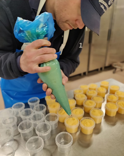 Närbild på Dennis som spritsar ut rom i små glas.