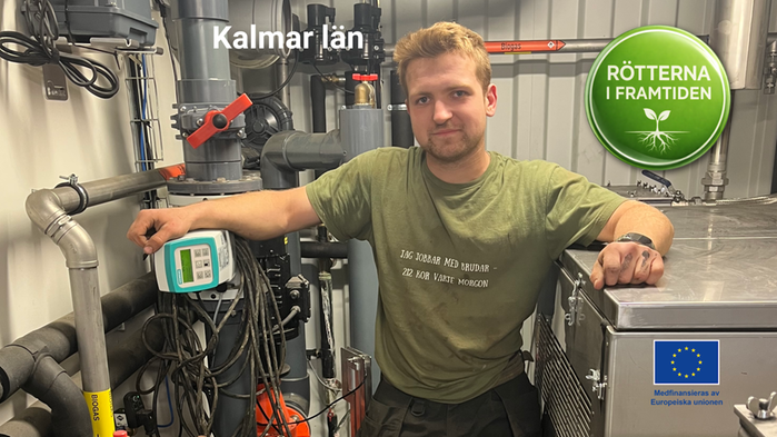 Erik Johansson har grön t-shirt och står i sin maskinhall på gården.