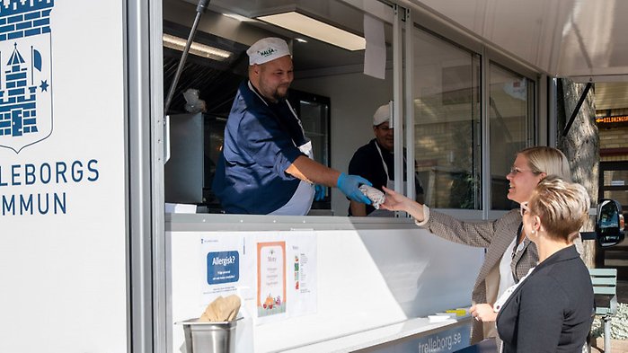 En kock i en Foodtruck serverar två damer mat. 