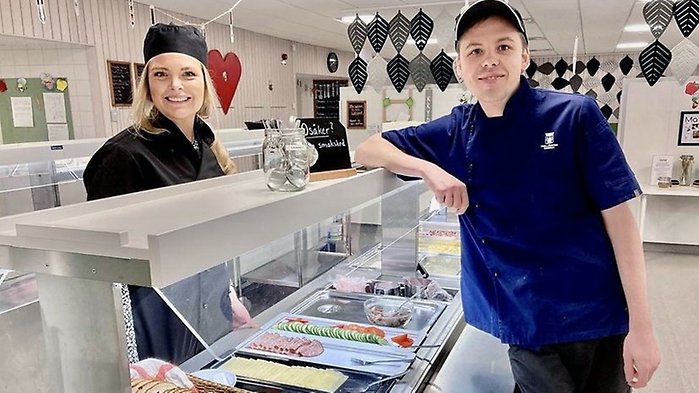 Frukostvärdinna och en person ur måltidspersonalen står vid buffévagn