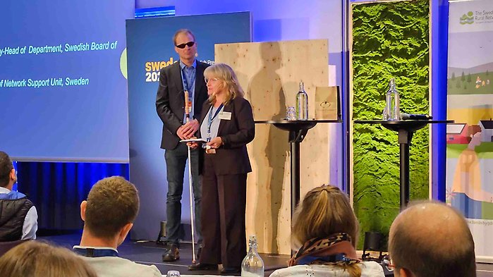 Andreas Mattisson och Maria Gustafsson på scenen i konferensrummet.