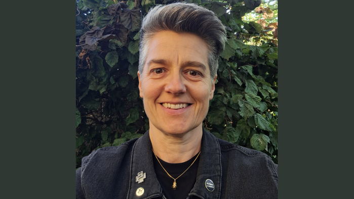 Helene Larsson Jönsson har grön jacka och mörk tröja och står utomhus