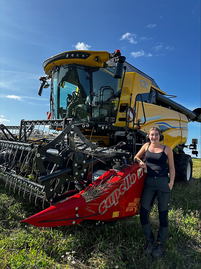Ung lantbrukare vid röd traktor