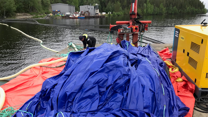 En uppsamlingsenhet monteras av en man under en fiskodlingskasse.