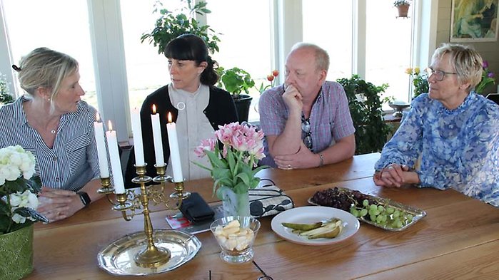 Fyra personer sitter i ett samtal,vid ett konferensbord.