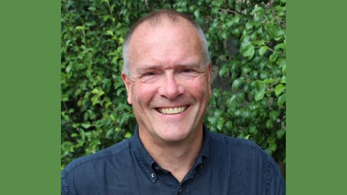 Lennart Wikström har marinblå skjorta och står framför ett träd i solsken