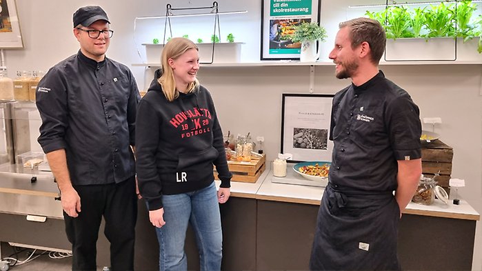 Kock, elev och måltidsutvecklare pratar i skolrestaurangen.