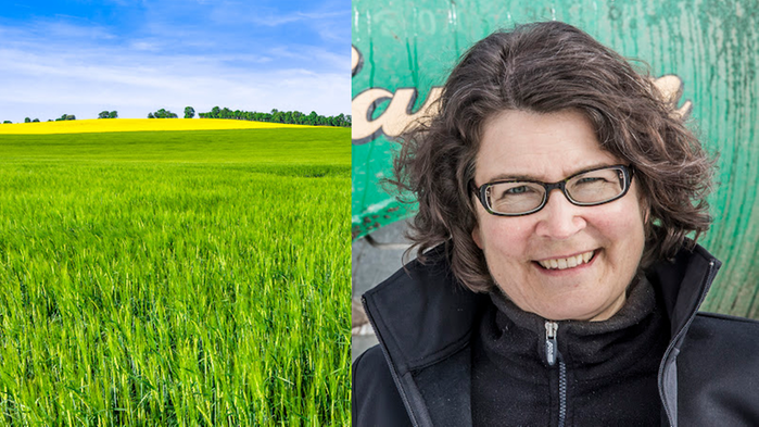 Eva Salomon har mörkt hår och en svart väst och står framför ett plank