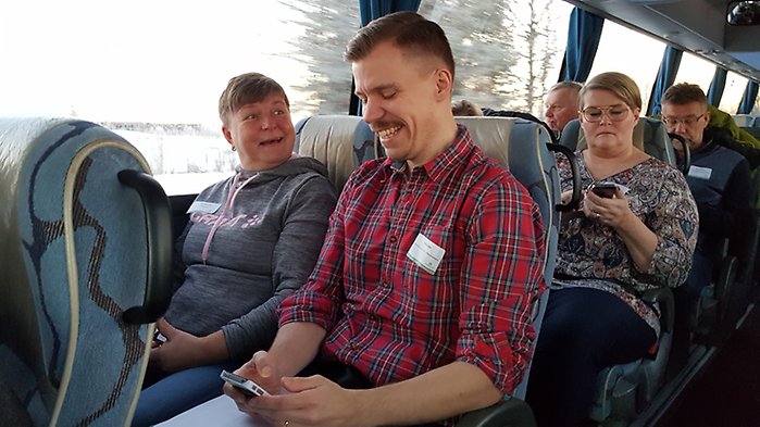 En man och en kvinna sitter och pratar med varandra på en buss.