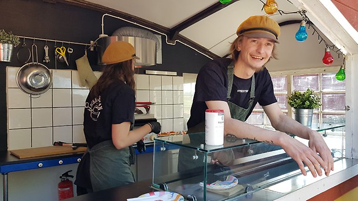 Filip Larsson, grundare av Stekosterian, står lutad över disken på sin food truck.