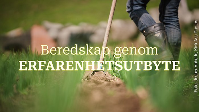 En person går över ett odlat fält med en hacka i handen